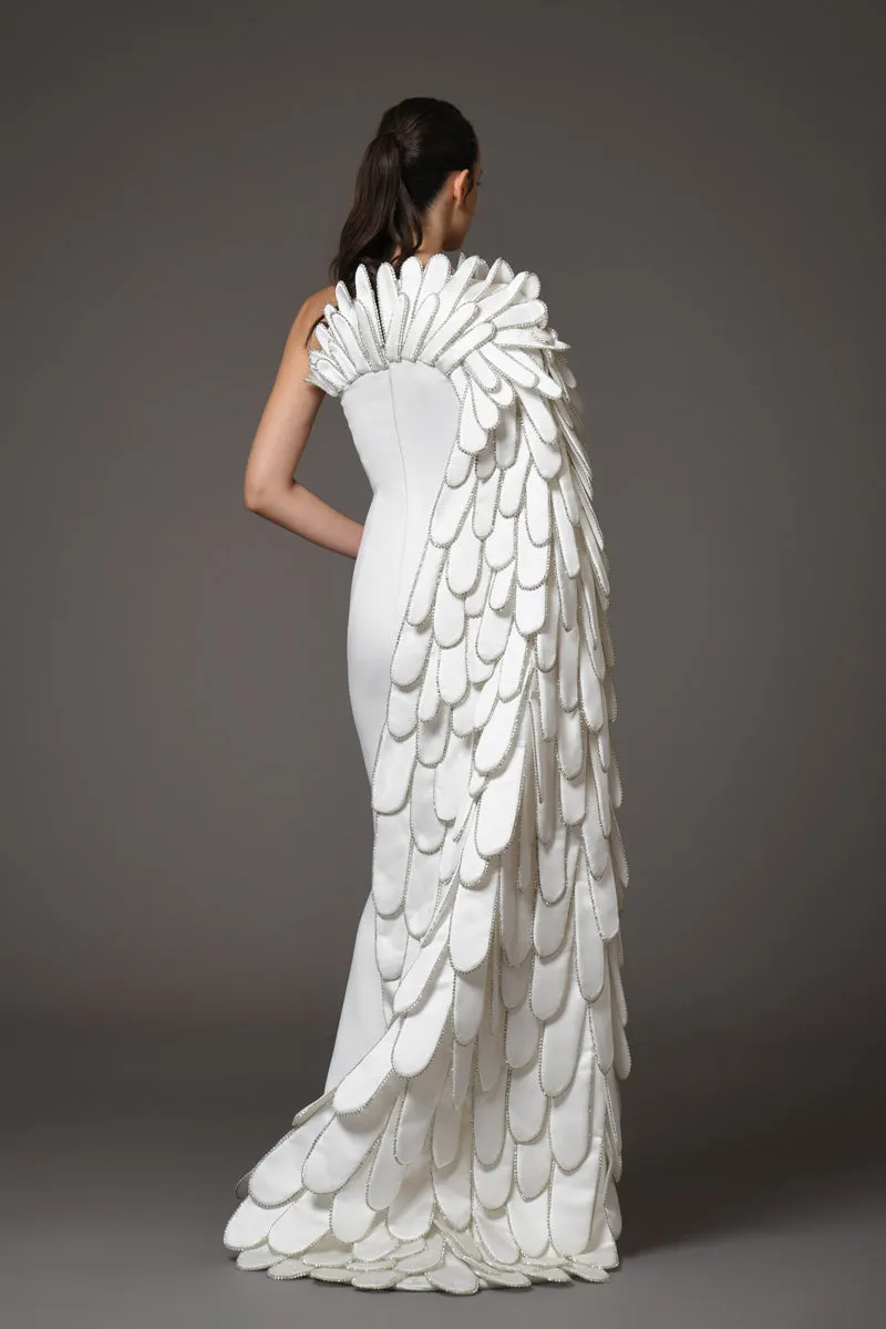 A sculpted gown in white silk scuba paired with layers of 3D hand-crafted plumes emerging from the bust into a cape
